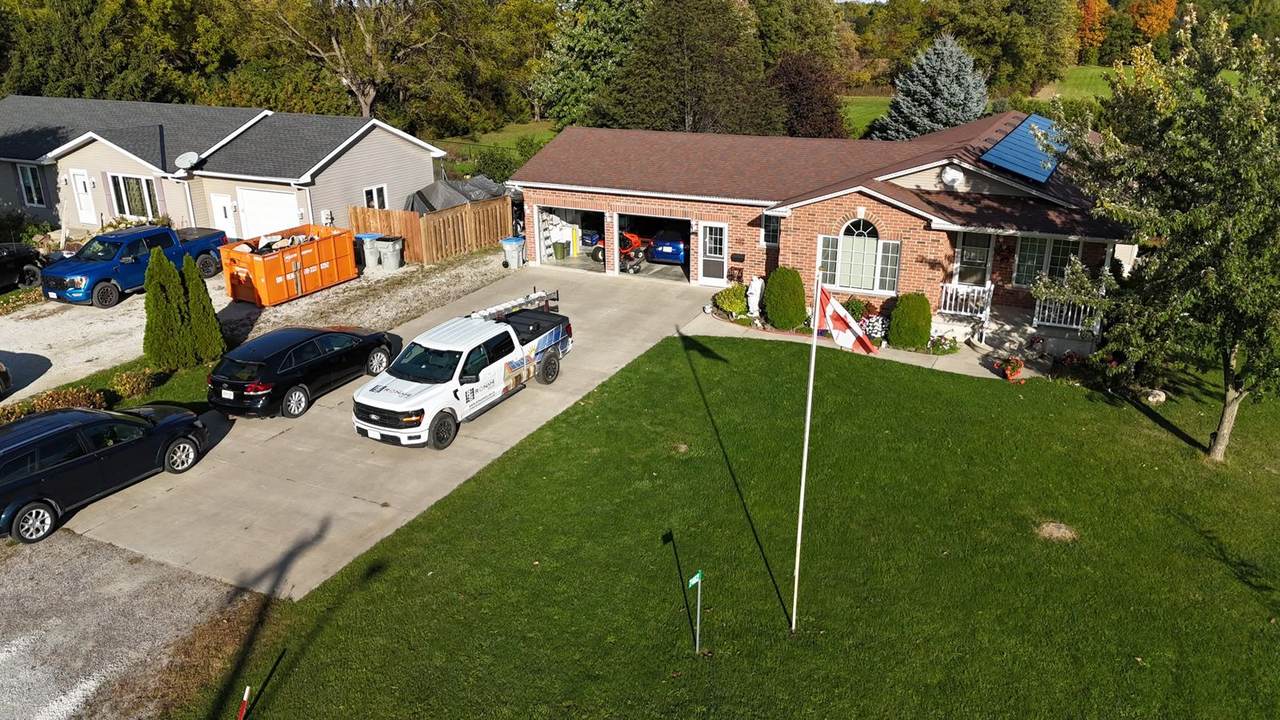 Ronahi Solar truck in the driveway of a brick home with solar panels and an attached garage
