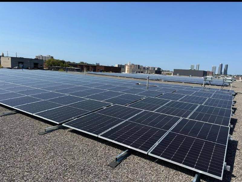 Commercial flat-roof solar array with the city skyline behind it