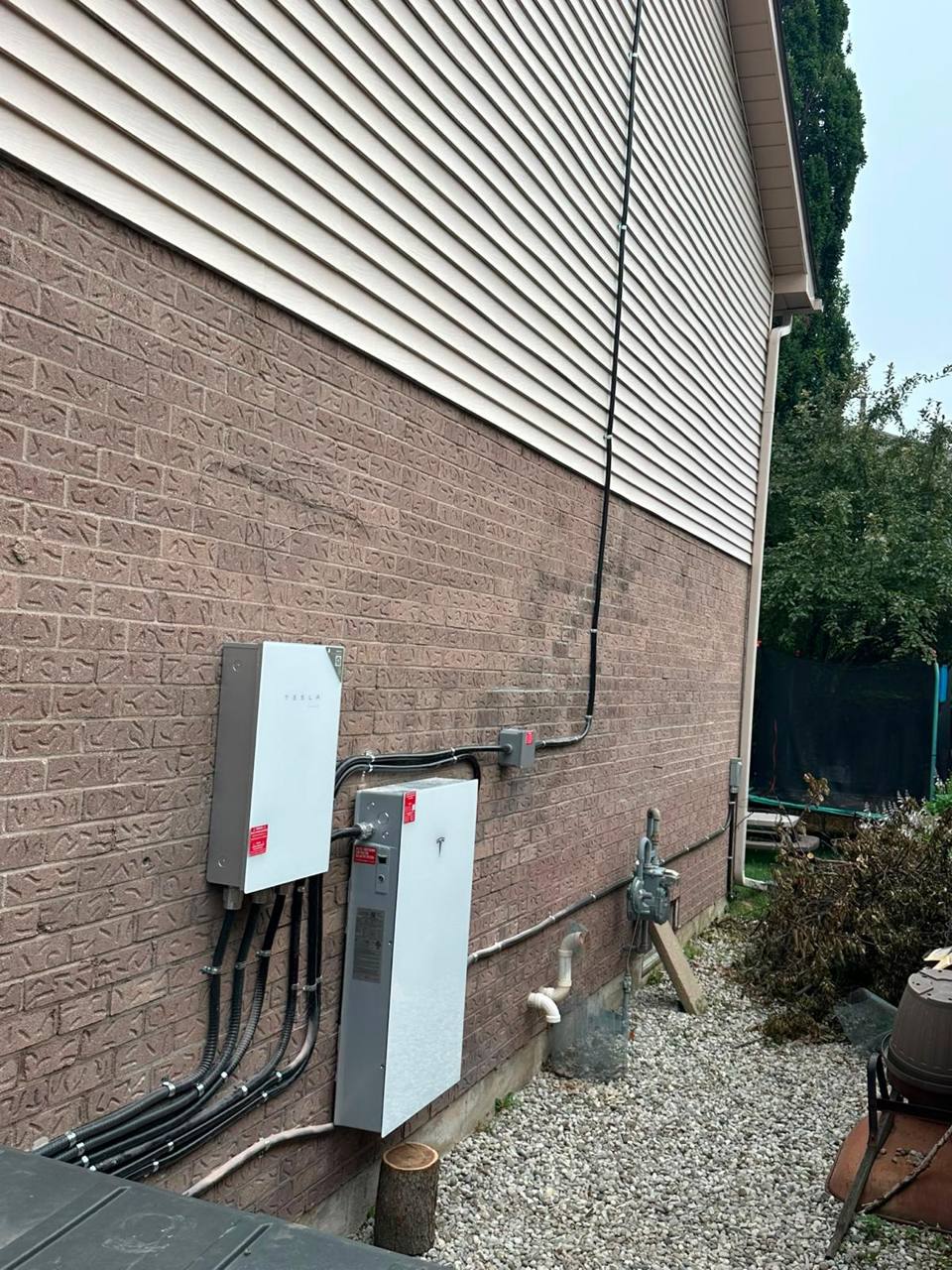 Tesla Powerwall and Gateway on a customer's home, conduit running up to the roof array